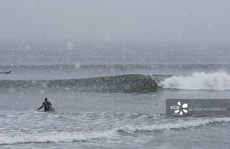 缅因州希金斯海滩暴风雪中走向海浪的冲浪者图片素材
