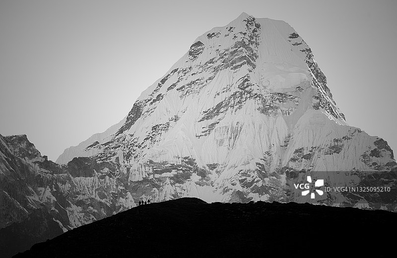 在尼泊尔萨加玛塔国家公园，以阿玛达布拉姆山（6812米）山坡为背景的徒步者剪影（黑白照片）图片素材