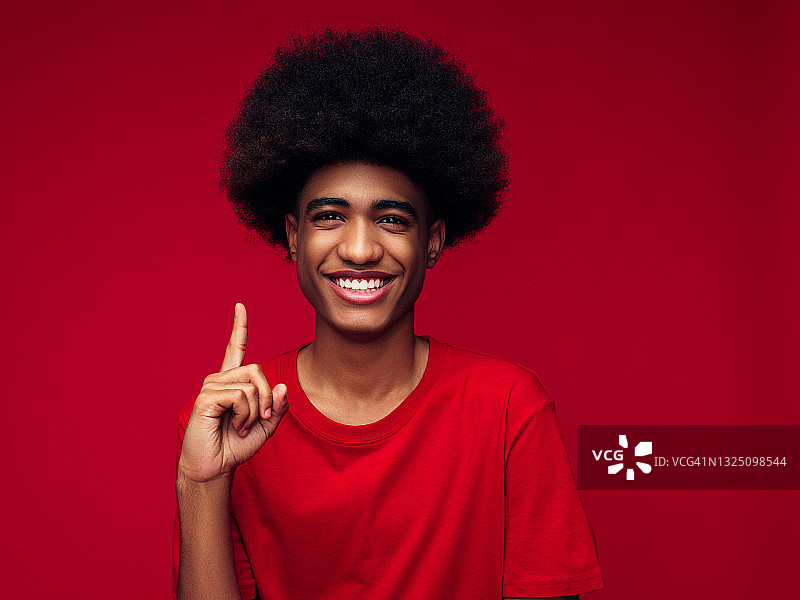 头戴帽衫的非裔男子，站在红色背景前图片素材