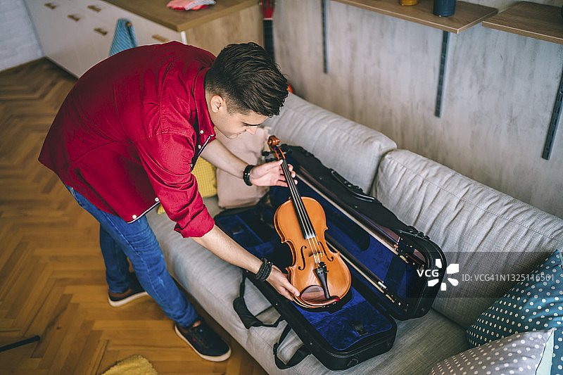 男人将小提琴放入琴盒图片素材