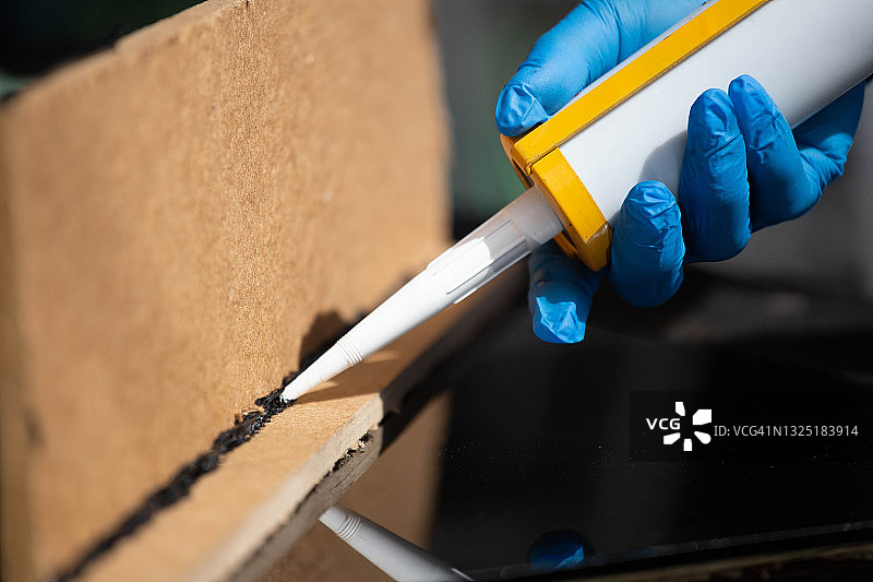 用硅胶和热熔胶枪紧密拉伸铝和玻璃特写图片素材