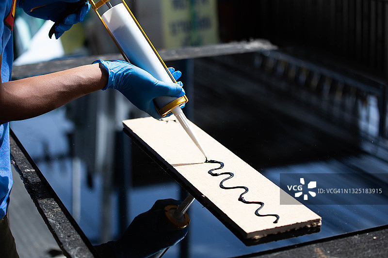 用硅胶和热熔胶枪紧密拉伸铝和玻璃特写图片素材