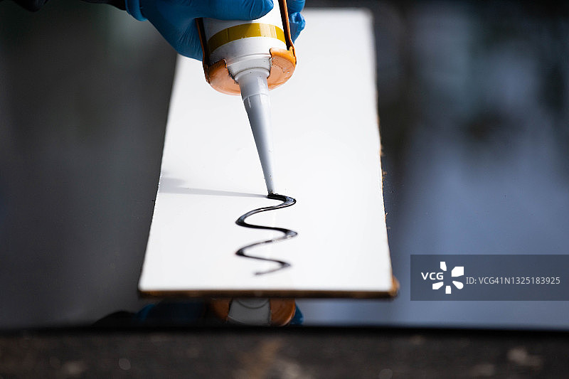 用硅胶和热熔胶枪紧密拉伸铝和玻璃特写图片素材