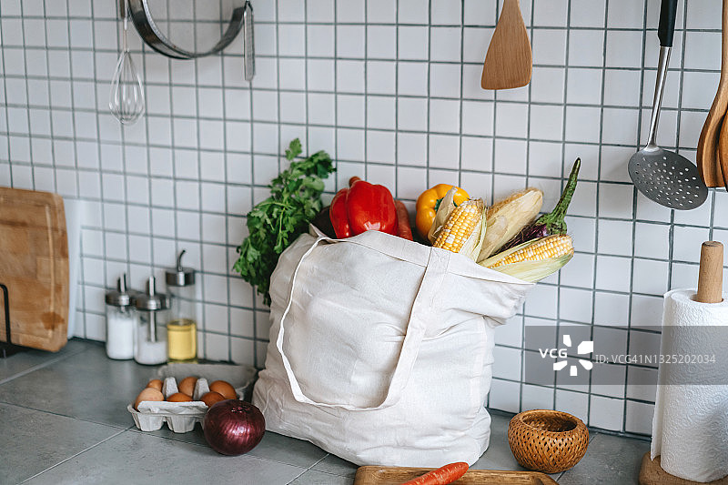 可重复使用的购物袋，装满新鲜的有机蔬菜和食品，放在厨房的台面上。零浪费购物和可持续生活方式理念图片素材
