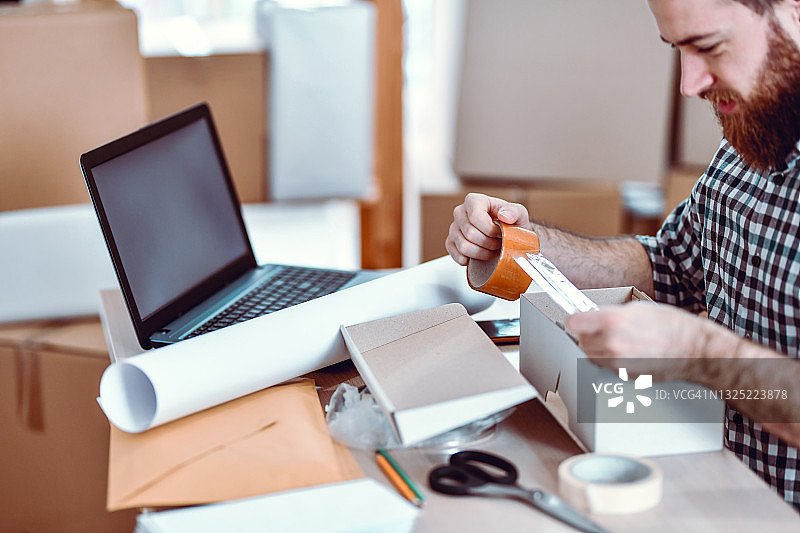 折叠包裹时使用胶带的络腮胡办公室职员图片素材