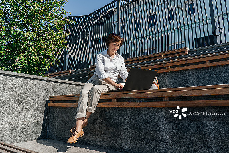 在城市长椅上工作的女商人图片素材