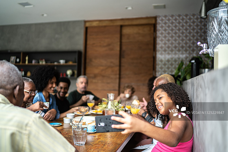 女孩在家庭早餐时自拍或进行视频通话图片素材