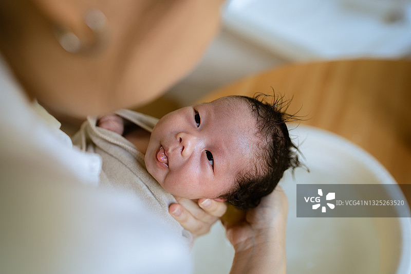 母亲在家给婴儿穿衣服图片素材