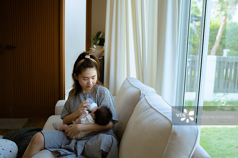 年轻的母亲给怀里的小新生婴儿喂奶图片素材