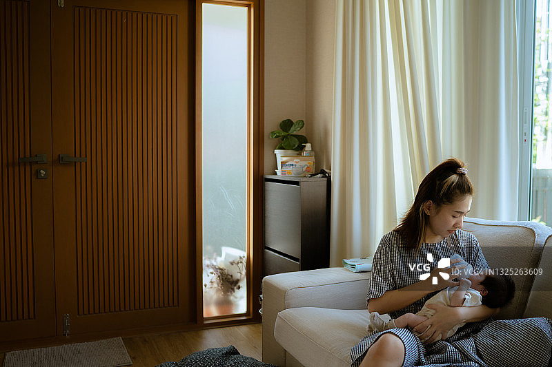 年轻的母亲给怀里的小新生婴儿喂奶图片素材