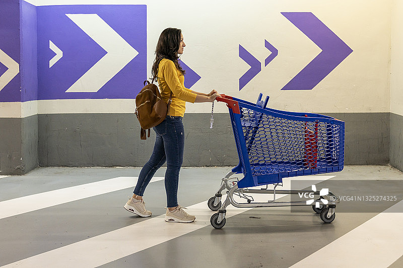 年轻女人在超市车库里推着空购物车图片素材