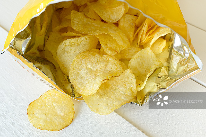 炸薯片从包装袋中洒落在白色背景上图片素材