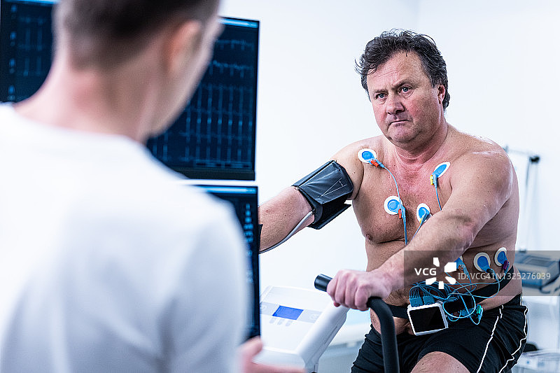 医生在实验室的健身车上监测成年男性的生物特征测试图片素材