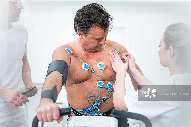 医生在生物识别测试前将电极连接到中年男人的躯干上图片素材
