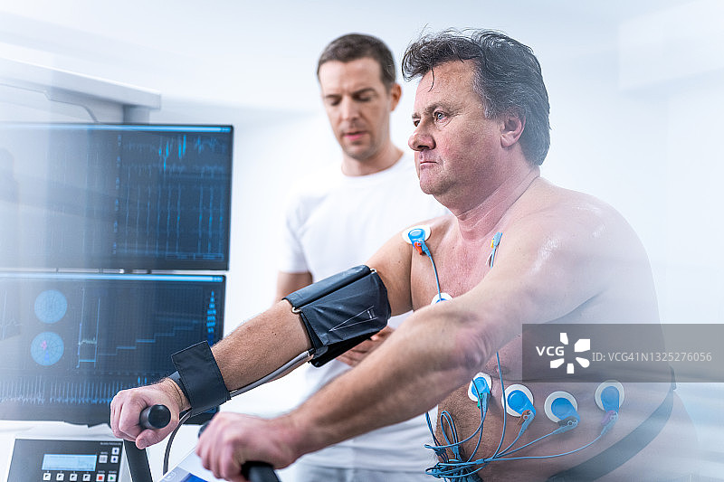 医生在实验室的健身车上监测成年男性的生物特征测试图片素材