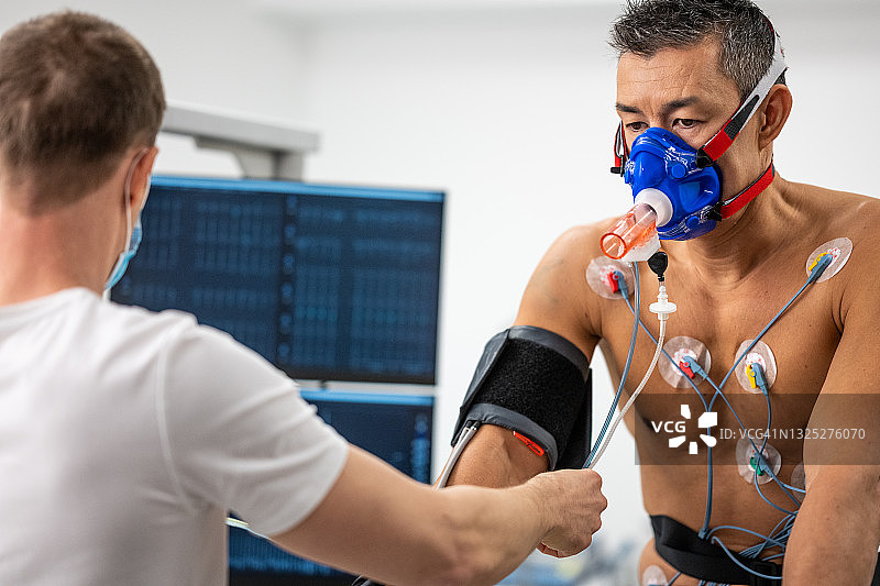 医生在动感单车上监测运动员的生物测试图片素材