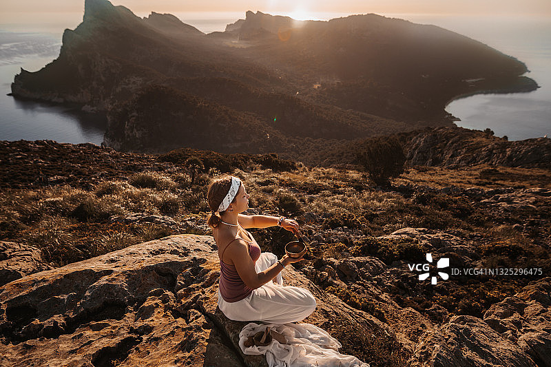 在山中冥想的瑜伽女孩，使用西藏颂钵图片素材