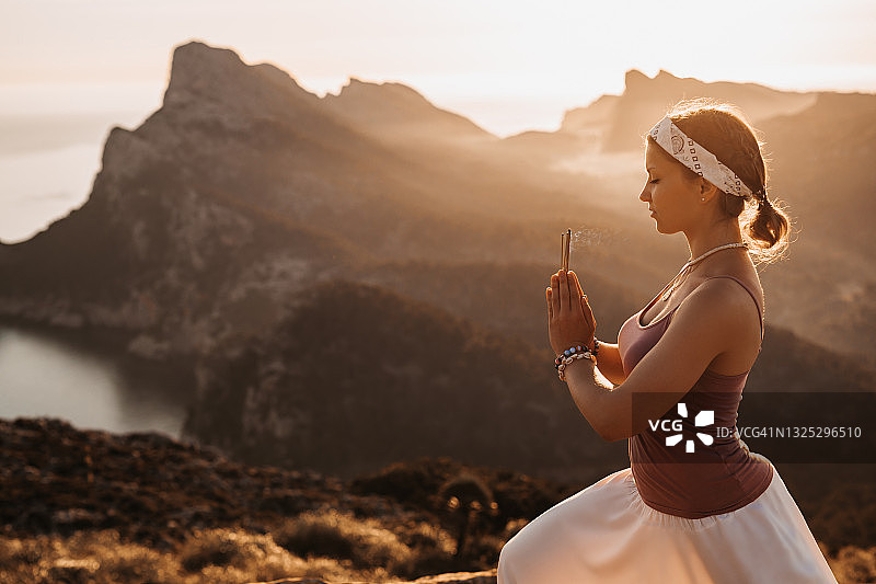 沉思的女人闭上眼睛做冥想站在香在日出在山区景观图片素材