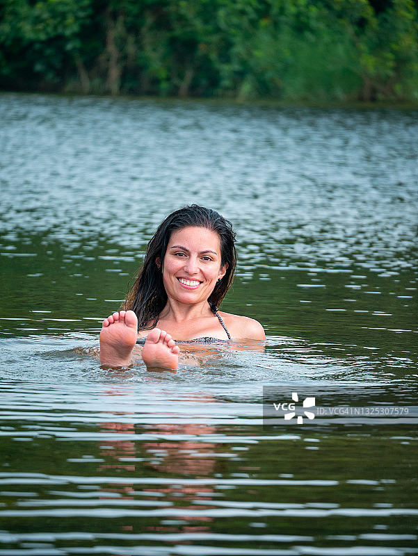 在哥伦比亚瓜希拉省帕洛米诺的圣萨尔瓦多河中游泳的年轻拉丁裔女子，展示她的双脚图片素材