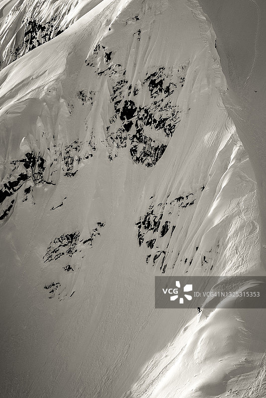 极限滑雪者滑下雪山山脊图片素材