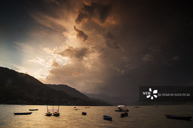 尼泊尔博卡拉费瓦湖上暴风雨天气的金色日落云和阳光图片素材