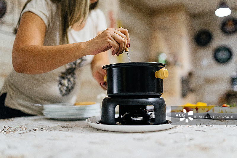 女人在桌旁准备奶酪火锅图片素材