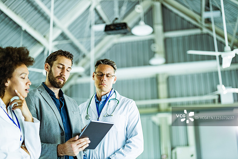 男商人和医生在医院的触摸板上工作图片素材