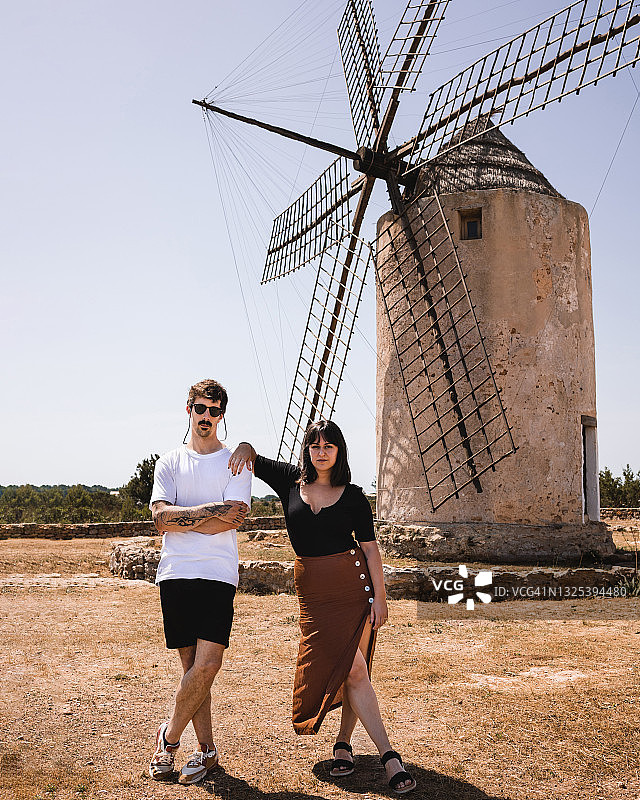 晴天风车旁摆姿势的年轻夫妇图片素材