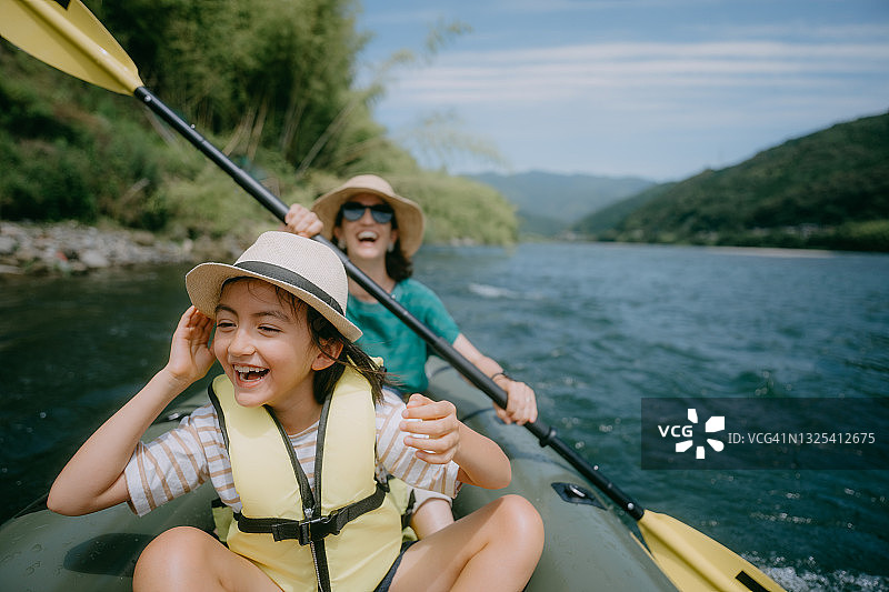 年轻女孩和母亲享受在日本的河流皮划艇之旅图片素材