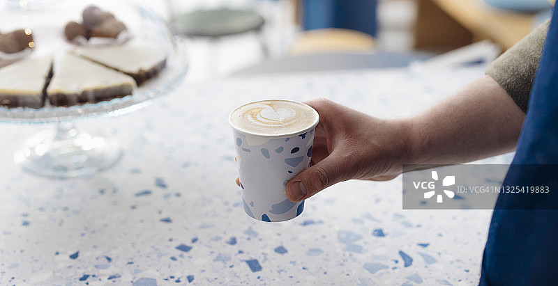 咖啡师在咖啡店里提供外卖纸杯咖啡图片素材