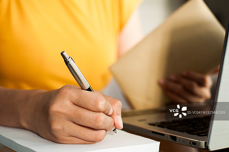 一位东南亚女性在办公室使用笔记本电脑处理财务图片素材