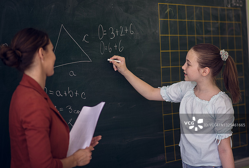 解数学题。学生用粉笔在黑板上书写。图片素材