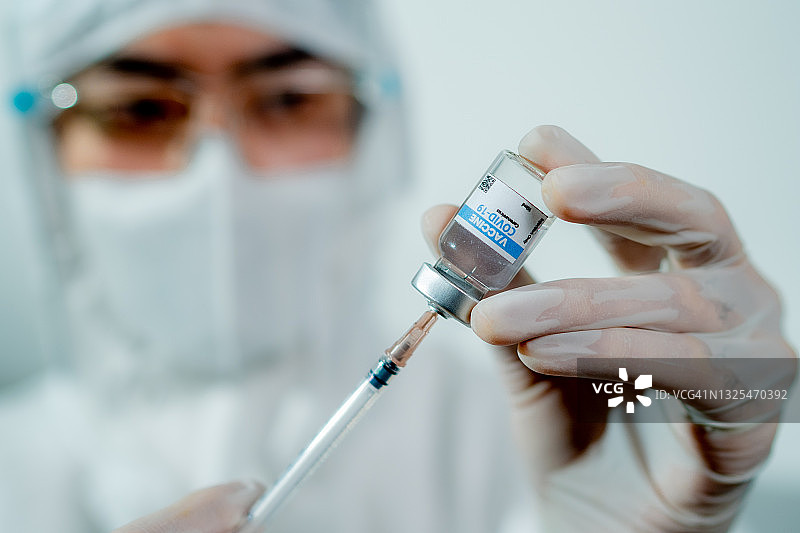 医生将疫苗从药瓶抽取到注射器中的肖像。图片素材