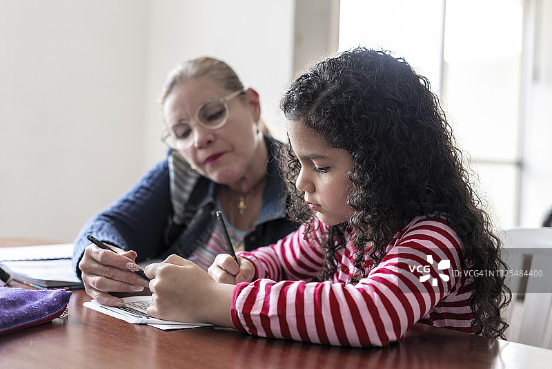拉丁裔妈妈帮助女儿做作业图片素材