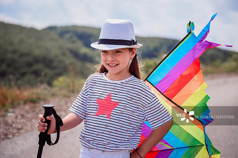 快乐的女孩拿着登山杖和风筝玩具图片素材