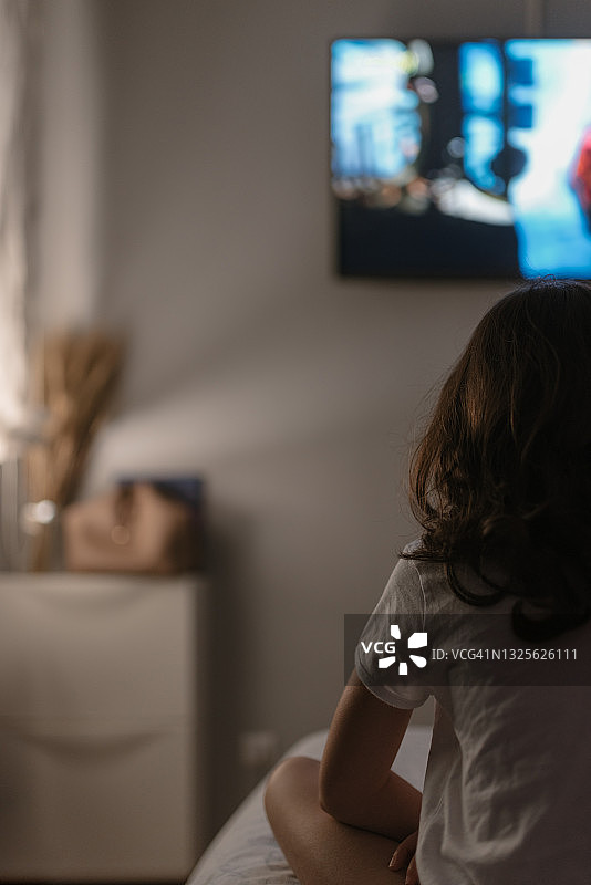 在床上看电视的年轻白人女孩的背影图片素材