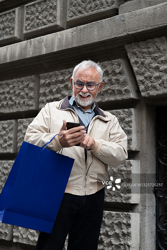 老年男人在市区行走并用手机发信息图片素材