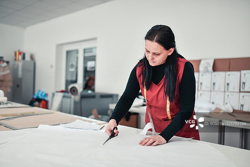现代女设计师在纺织厂裁剪布料图片素材