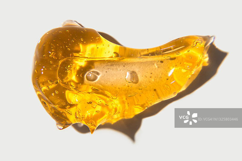 白色背景上的橙色凝胶透明涂抹，脱毛用黄色液体蜡或糖浆，无毛光滑肌肤脱毛概念banner图片素材