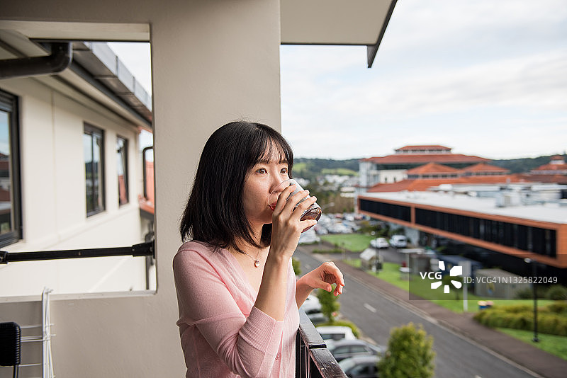 一个年轻的亚洲女人在阳台上享受早茶咖啡图片素材