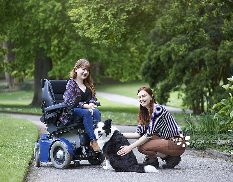 在公园里与朋友和狗在一起的残疾妇女图片素材