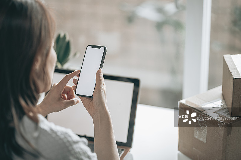 亚洲女人扫描包裹的二维码图片素材