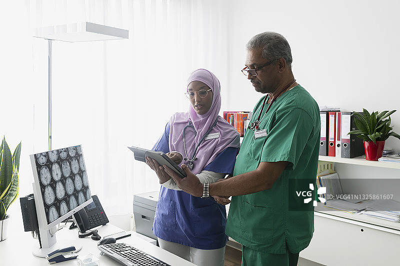 两位医生使用数字平板电脑讨论医学测试结果图片素材