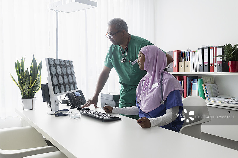 医生讨论电脑屏幕上的CT X光图像图片素材