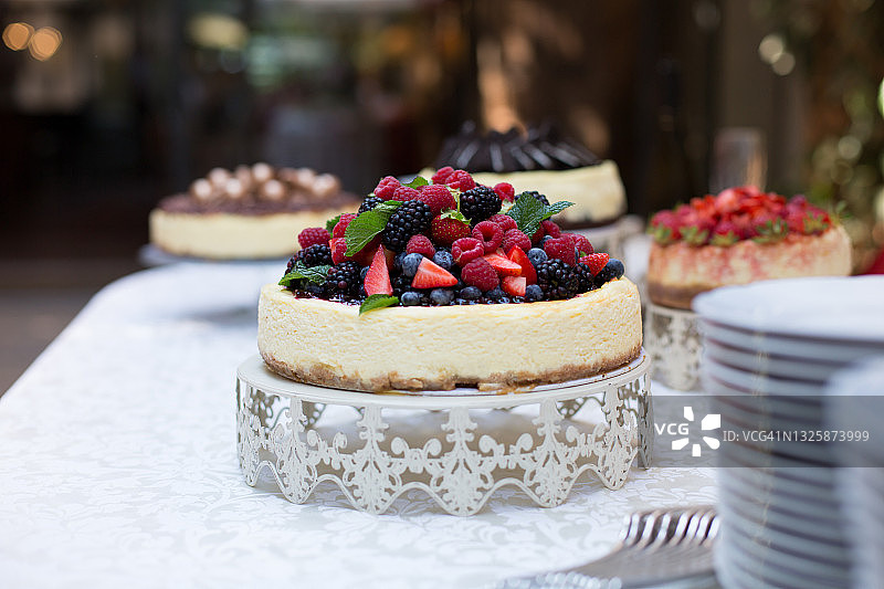 桌子上的蛋糕和盘子，焦点是浆果和新鲜薄荷叶的芝士蛋糕图片素材