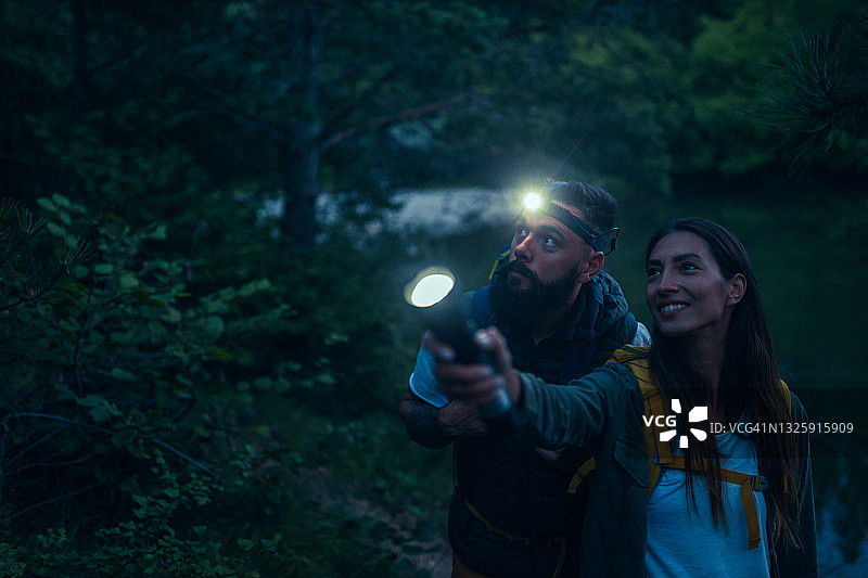 年轻情侣在树林里拿着手电筒图片素材