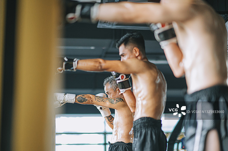 低角度：健身房内一排亚洲泰拳运动员日常拳击训练图片素材