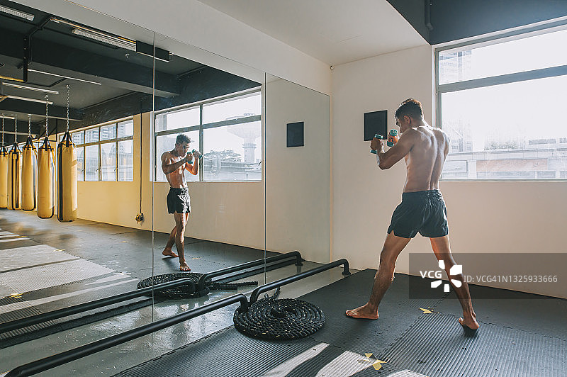 在镜子前练习的亚洲泰拳拳击手影子拳击空中出拳图片素材