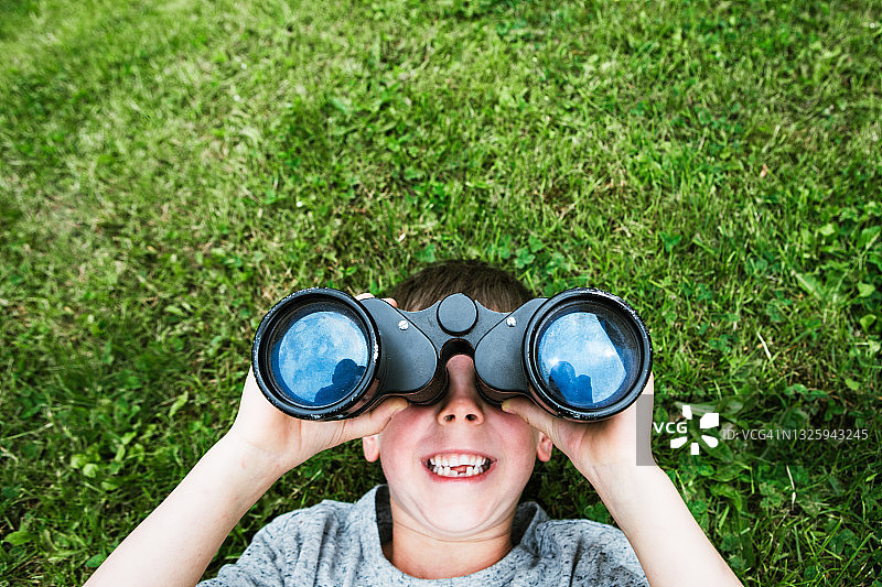 男孩用双筒望远镜看云图片素材