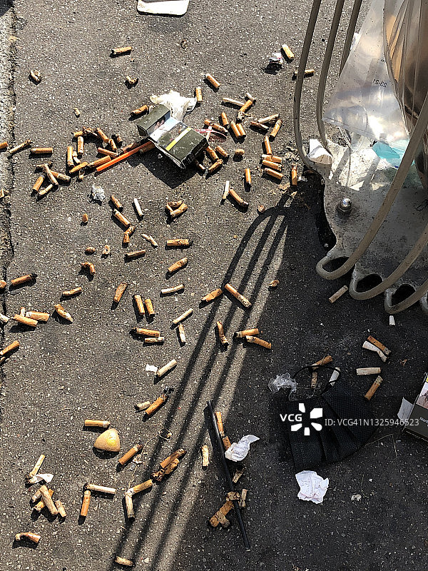 垃圾桶旁街道上乱扔的烟头图片素材